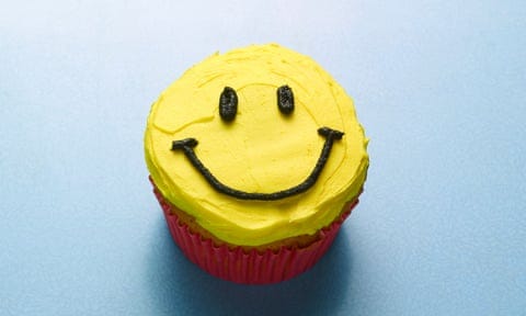 A cupcake with a smiley yellow face