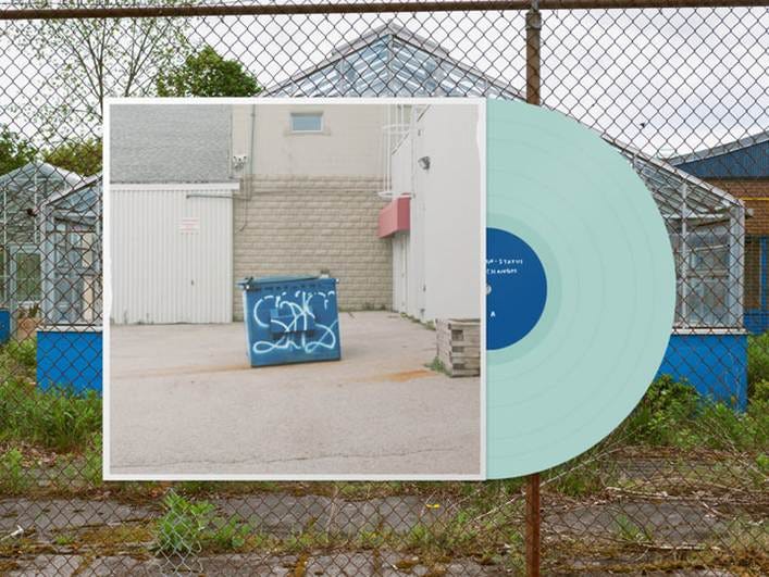 The image shows a blue vinyl record on a table, a wall with graffiti, and a chain-link fence in the background.
AI-generated content may be incorrect. The image shows a blue vinyl record on a table, a wall with graffiti, and a chain-link fence in the background.
AI-generated content may be incorrect.