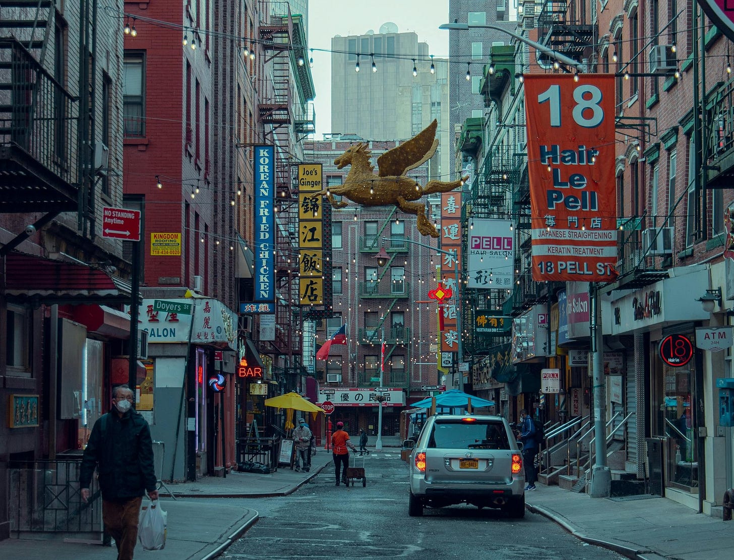 A street in NYC Chinatown with signs in English and Chinese 