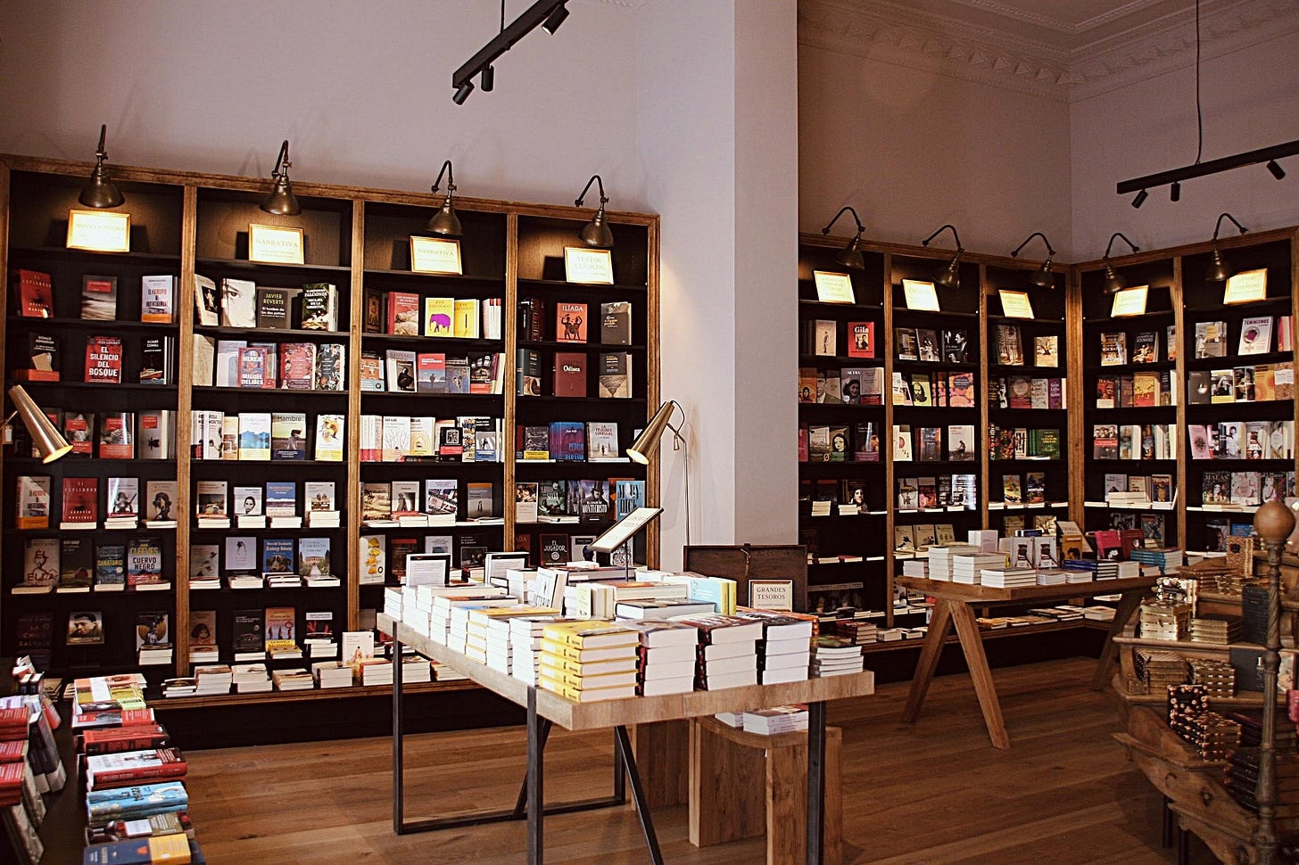 Interior de una librería con estanterías llenas de libros y mesas con libros apilados Interior de una librería con estanterías llenas de libros y mesas con libros apilados