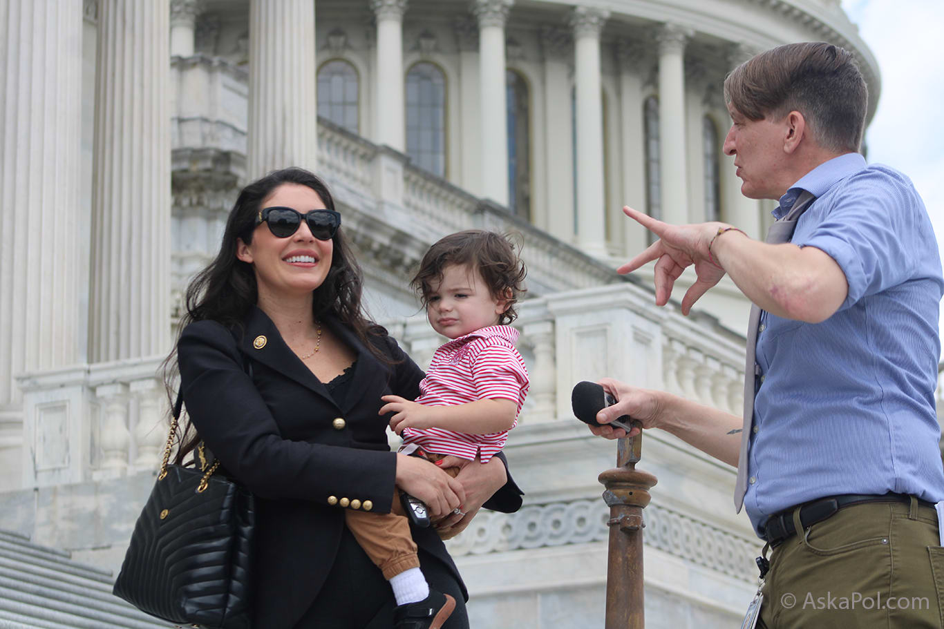 Lady in glasses holds baby as reporter asks questions Photo: Logan Johnson © Ask a Pol Lady in glasses holds baby as reporter asks questions Photo: Logan Johnson © Ask a Pol