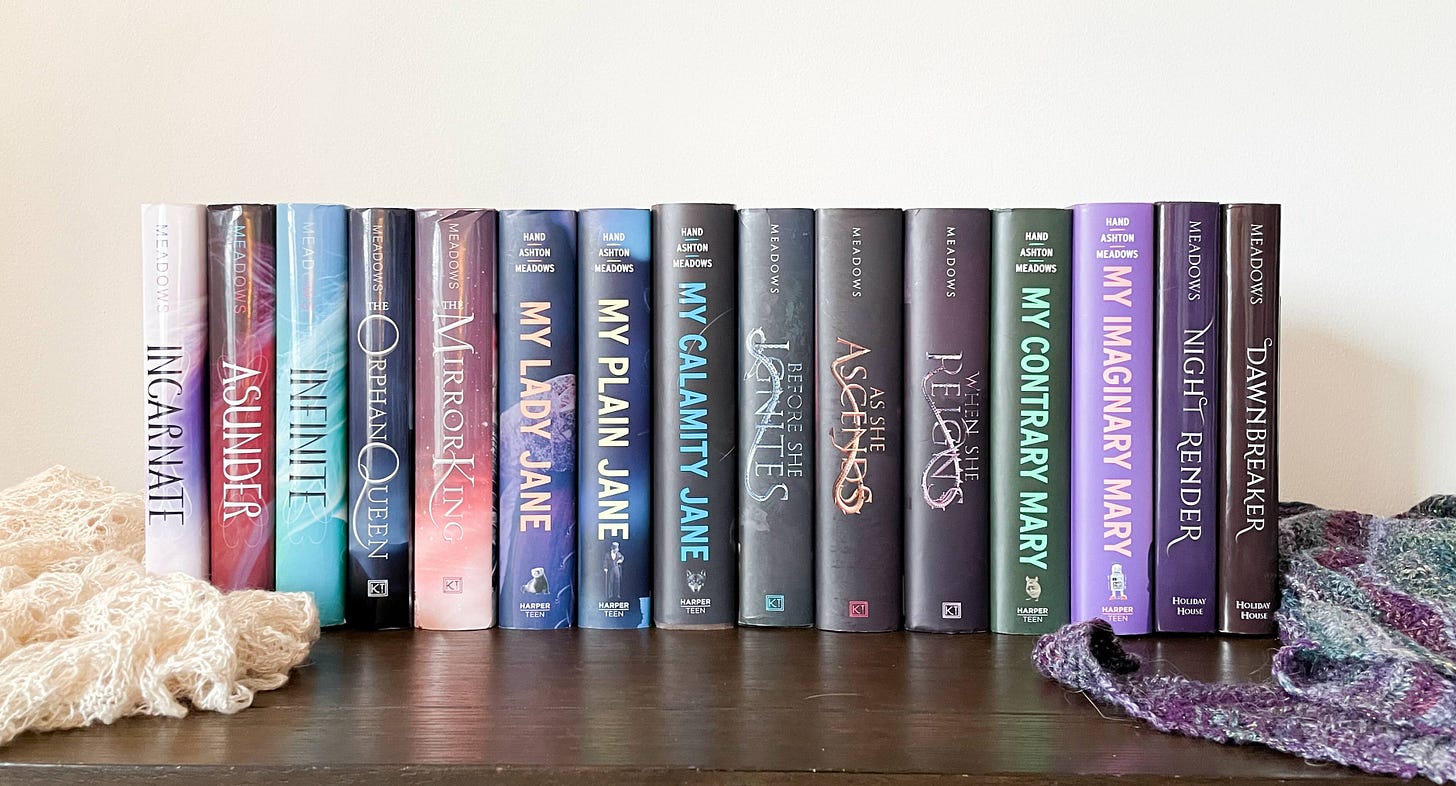 My published books lined up, a knit shawl on either side of them.