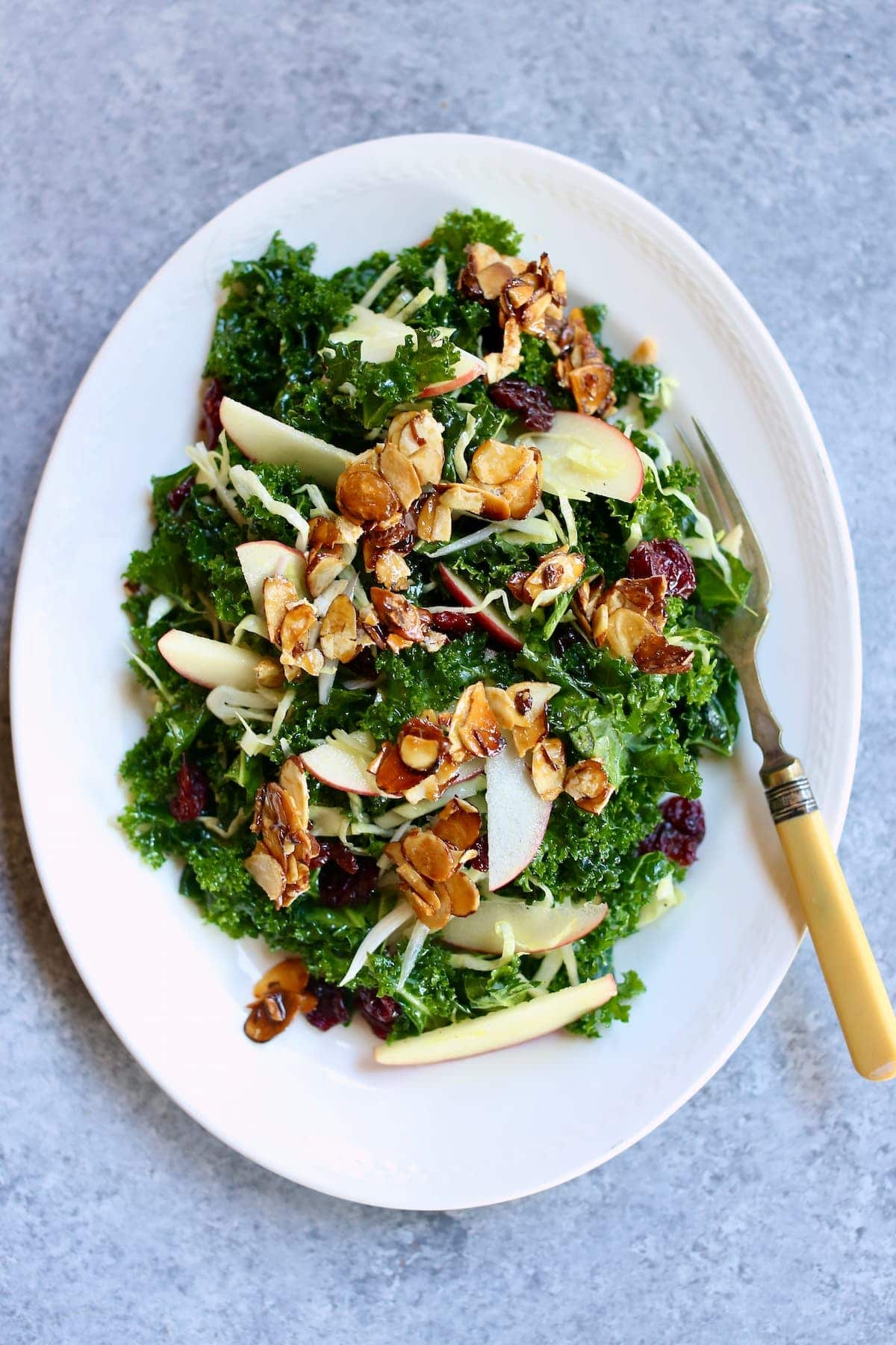 a white platter with a kale salad on it.