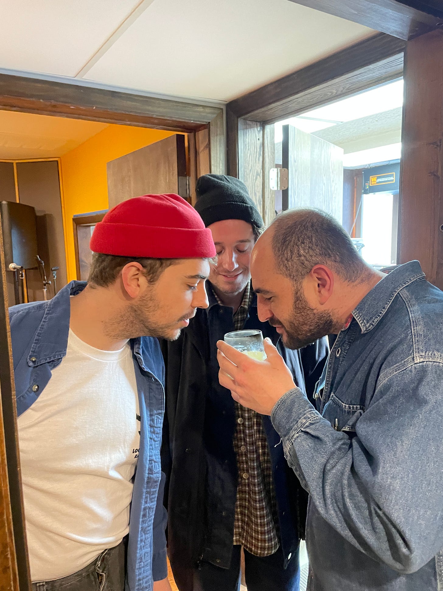Friends Chet, Henry, and Max crowding their noses around a candle to smell it.