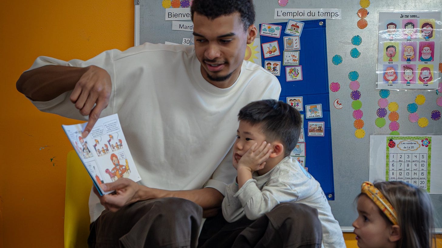Victor Wembanyama reads a French book to a young child at the International School of San Antonio Victor Wembanyama reads a French book to a young child at the International School of San Antonio