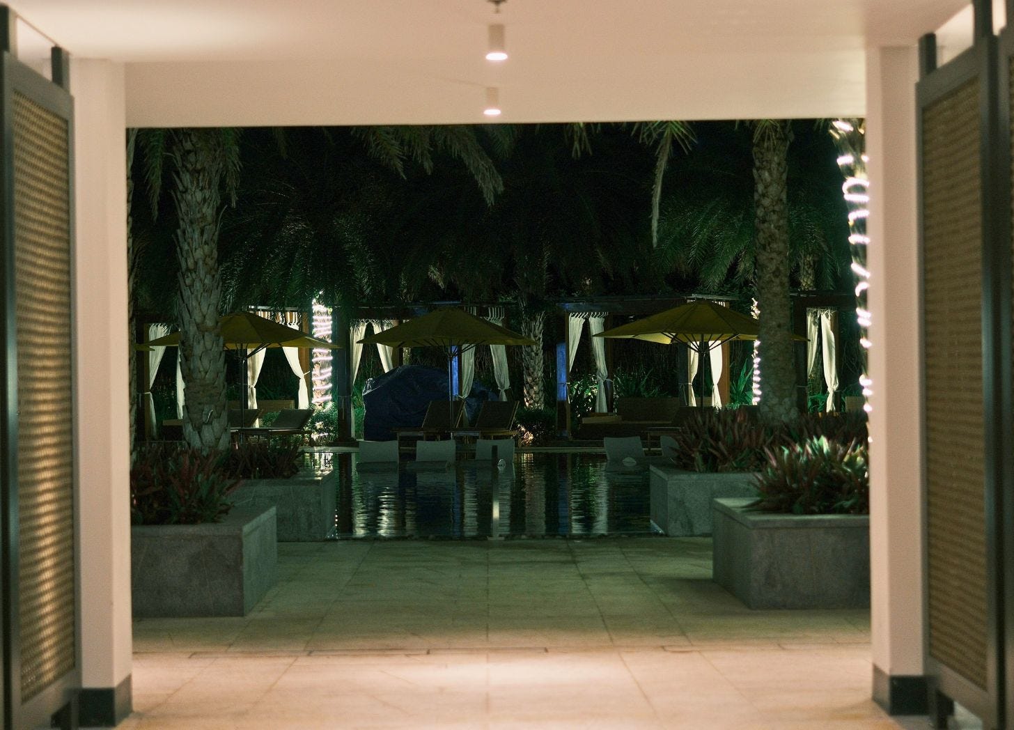 A quiet hotel arrival corridor at night, showing the in-between moment where guests orient themselves before entering the property. A quiet hotel arrival corridor at night, showing the in-between moment where guests orient themselves before entering the property.