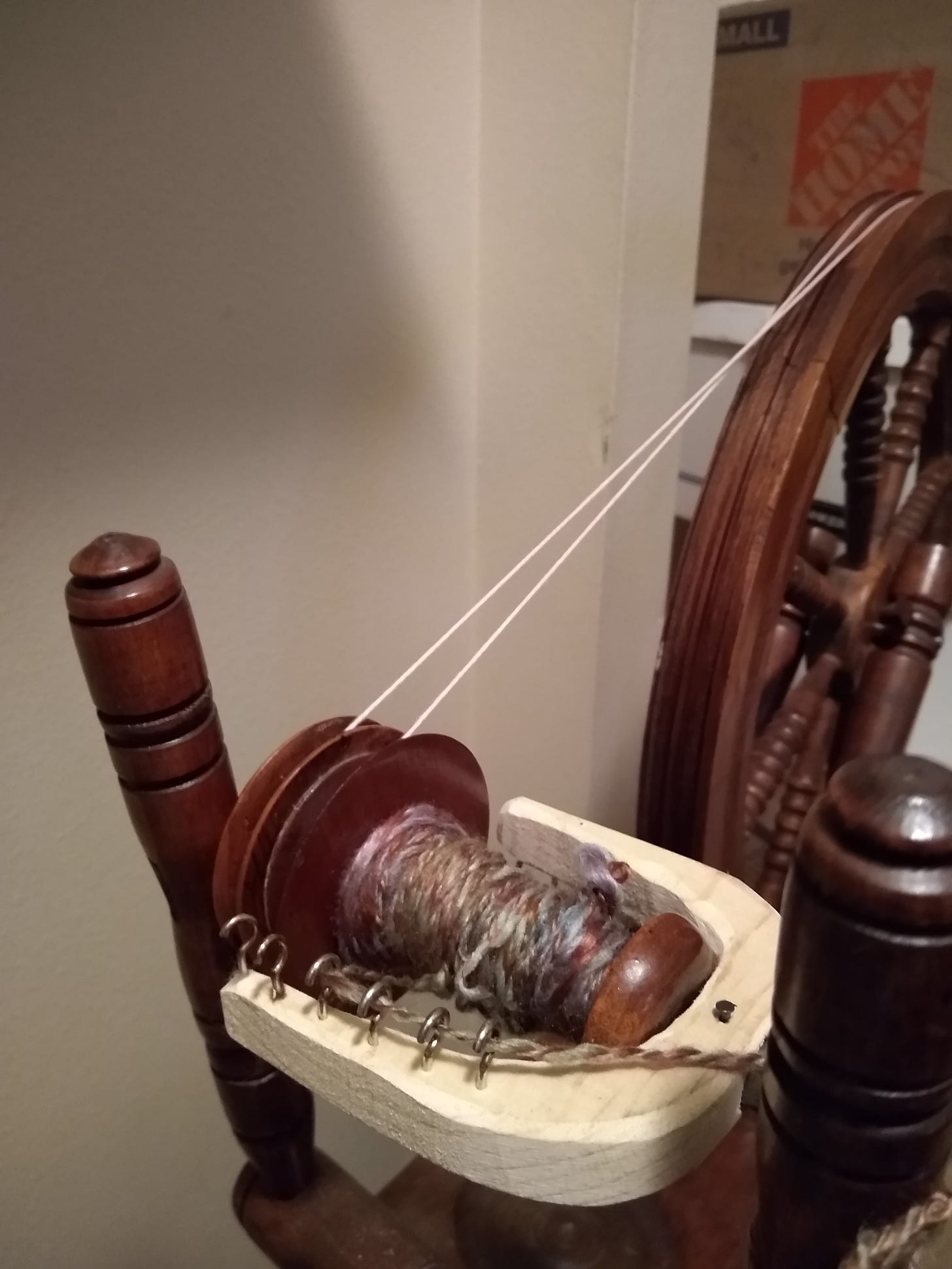 Shiny purples, yellows, greens, and blues on a spinning wheel bobbin