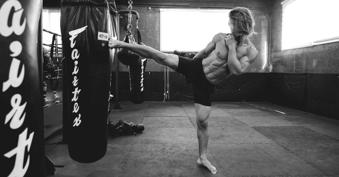 A man doing a kickbox kick in a gym