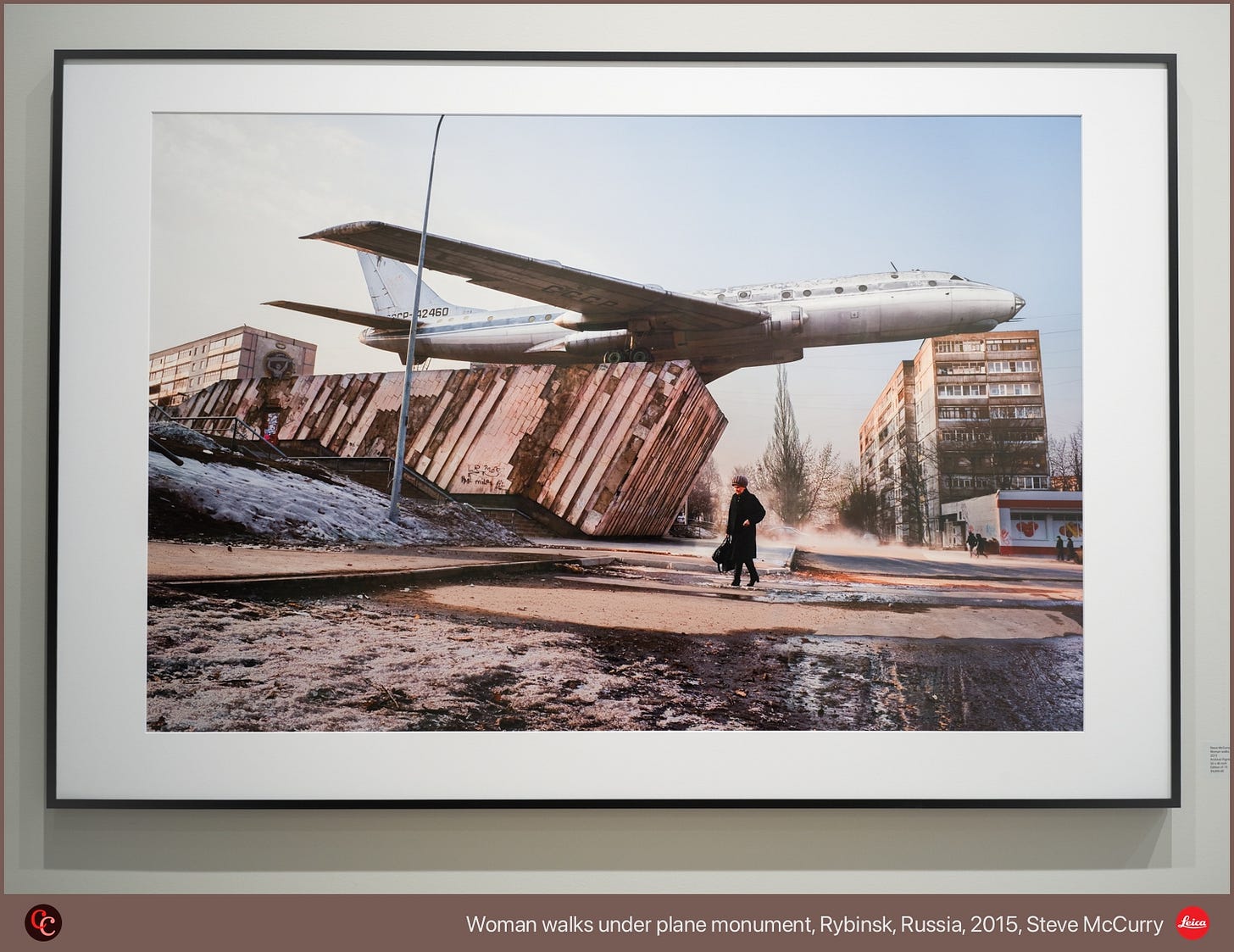 Woman walks under plane monument, Rybinsk, Russia, 2015, Steve McCurry Woman walks under plane monument, Rybinsk, Russia, 2015, Steve McCurry