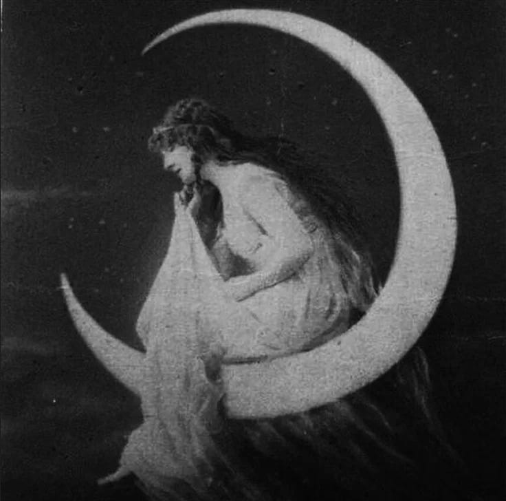 This may contain: a woman is sitting on the moon with her hands to her face and looking down