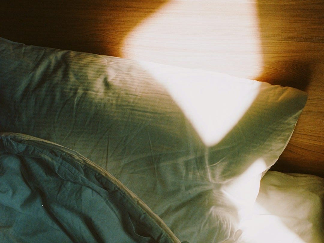 a bed with a white comforter and a wooden head board