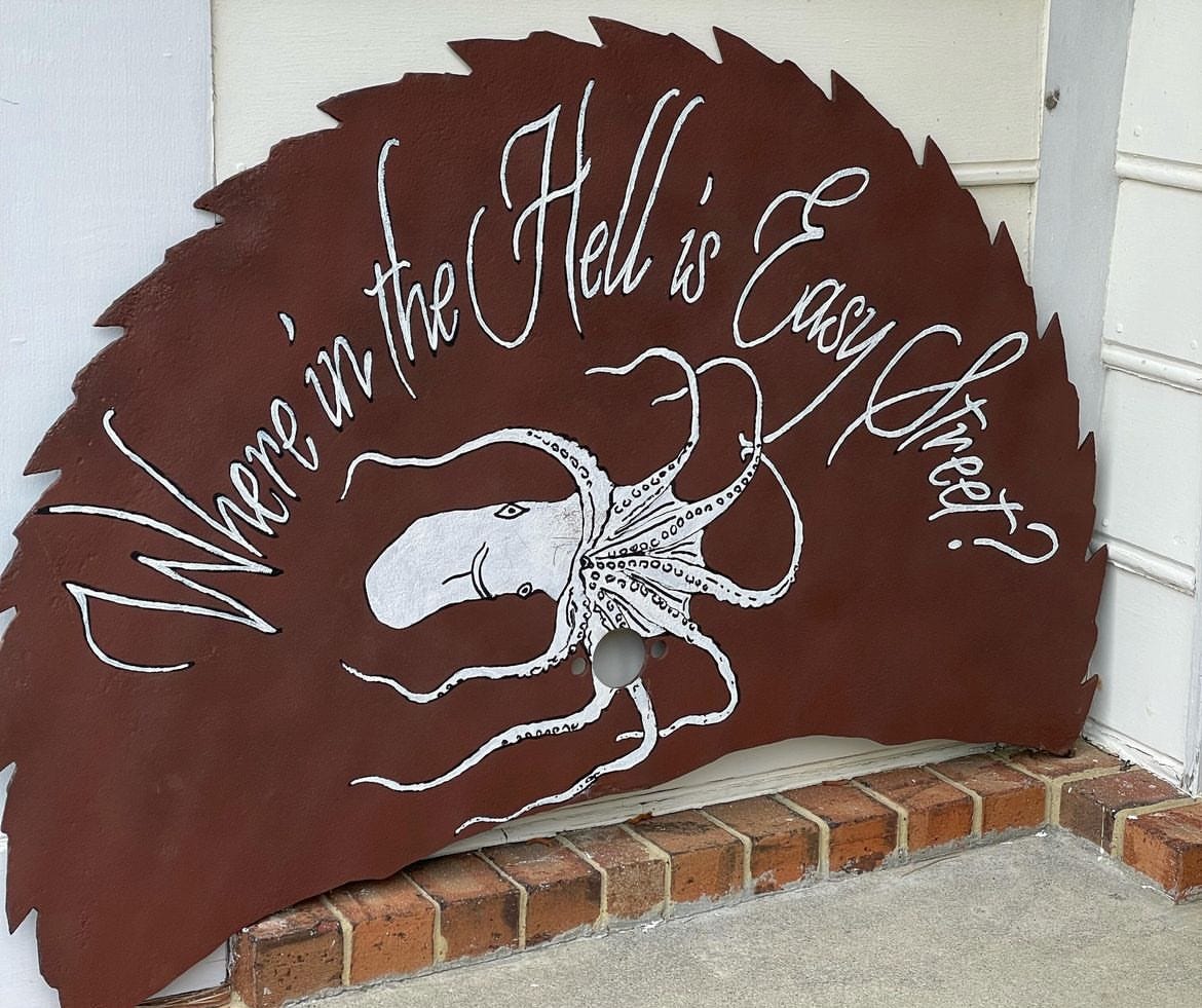 large rust colored saw blade with a handpainted octopus and the words "Where in the Hell is Easy Street?"