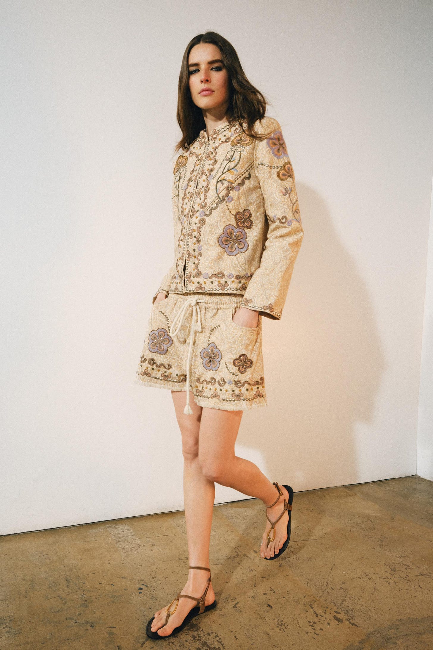 Jacket, multicolored floral embroidered Bermuda shorts, and sandals set. The Bermuda shorts feature an elastic waistband, drawstring, and side pockets. Jacket, multicolored floral embroidered Bermuda shorts, and sandals set. The Bermuda shorts feature an elastic waistband, drawstring, and side pockets.