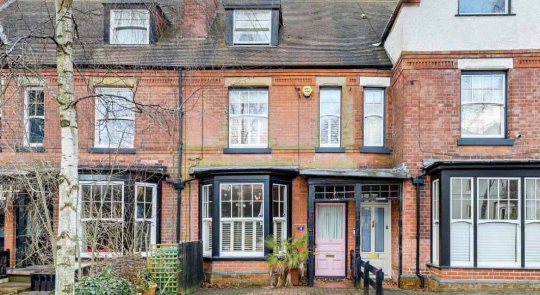 A row of houses with black framed windows, colourful doors, and a tree to the left A row of houses with black framed windows, colourful doors, and a tree to the left