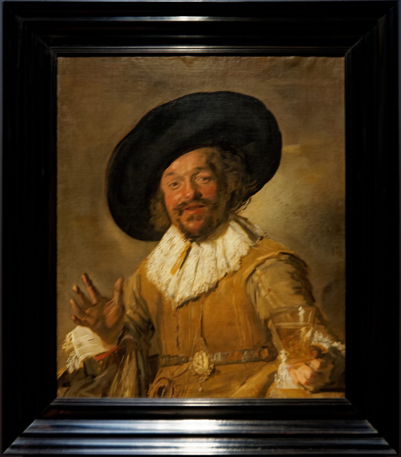 A man in a wide hat leaning toward you with a wine glass