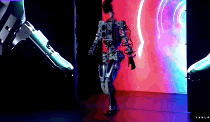 Animated GIF showing Tesla’s robot walk gingerly in front of a bright screen at the AI Day event.