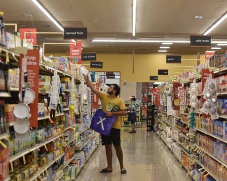 a man reaching for an item in a grocery store aisle