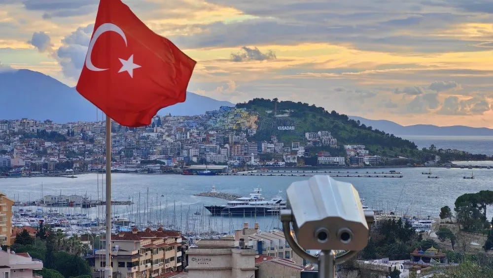 A bandeira turca tremula sobre o porto de Kusadasi, na costa oeste do Mar Egeu, na Turquia, ao pôr do sol. Shutterstock