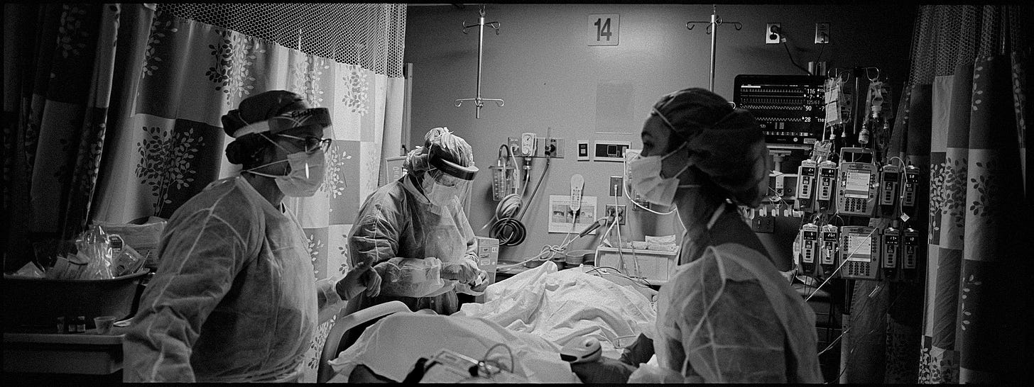 photo of a COVID-19 ICU ward from March 2020 with three healthcare workers standing over an intubated patient photo of a COVID-19 ICU ward from March 2020 with three healthcare workers standing over an intubated patient