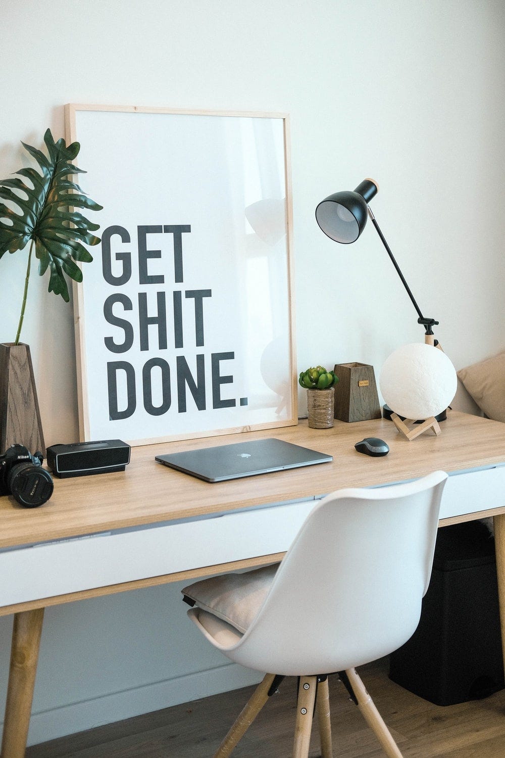 brown and white wooden desk with chair and laptop. "Get shit done" in a frame brown and white wooden desk with chair and laptop. "Get shit done" in a frame