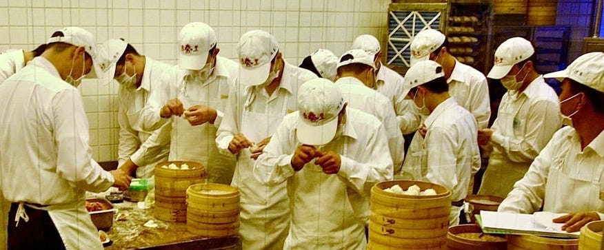 Chefs in white uniforms preparing food in a kitchen.