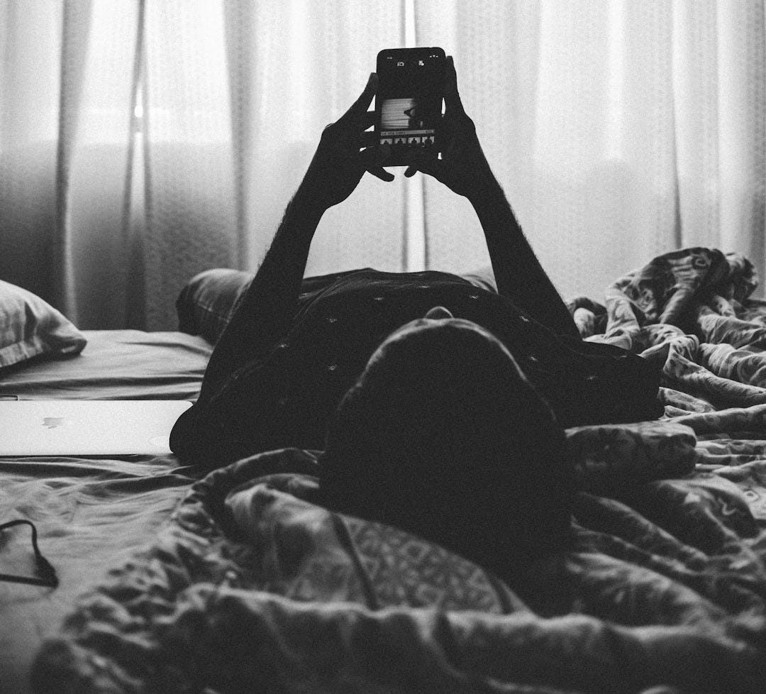 man lying on bed using smartphone