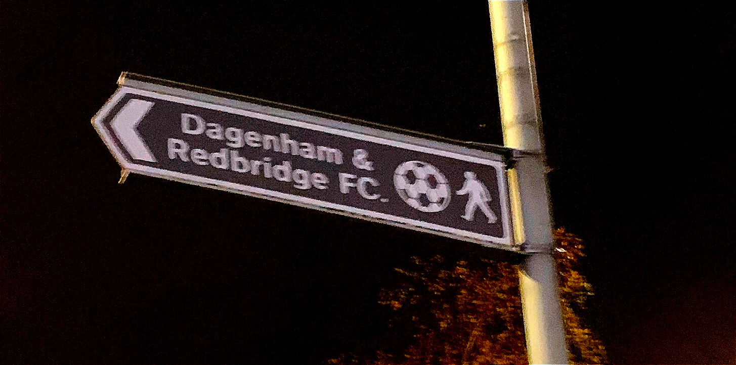 Brown road sign pointing towards Dagenham & Redbridge FC