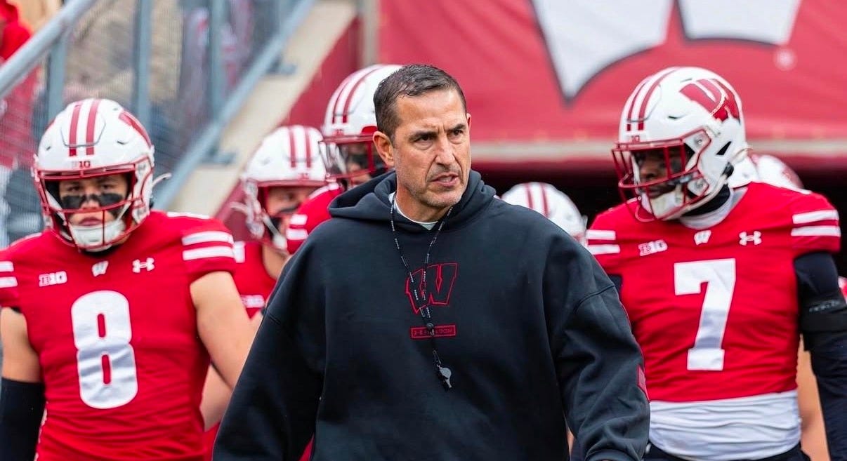 Wisconsin head coach Luke Fickell walks onto the field at Camp Randall Stadium in a black Under Armour Freedom Collection hoodie for Veterans Day recognition