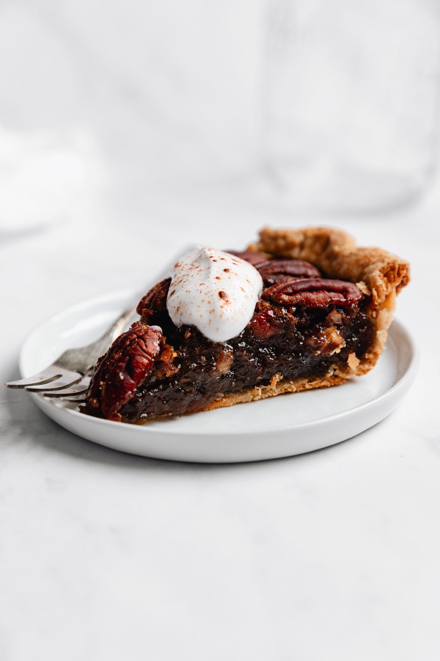 Slice of vegan chai spiced pecan pie on white background