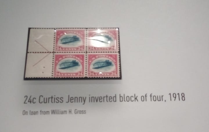 On left, block of four stamps showing upside down biplane. On the right, the entire museum display on this so-called Inverted Jenny stamp