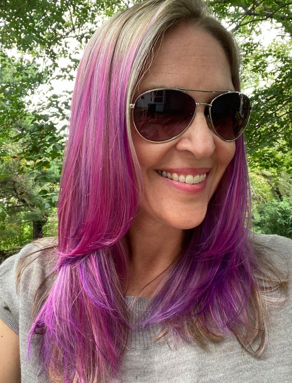 heather sweeney smiling with purple hair wearing sunglasses