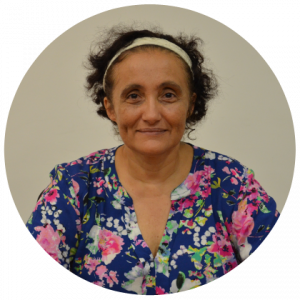 Mulher negra de cabelo preto curto e blusa colorida. Usa uma faixa na cabeça