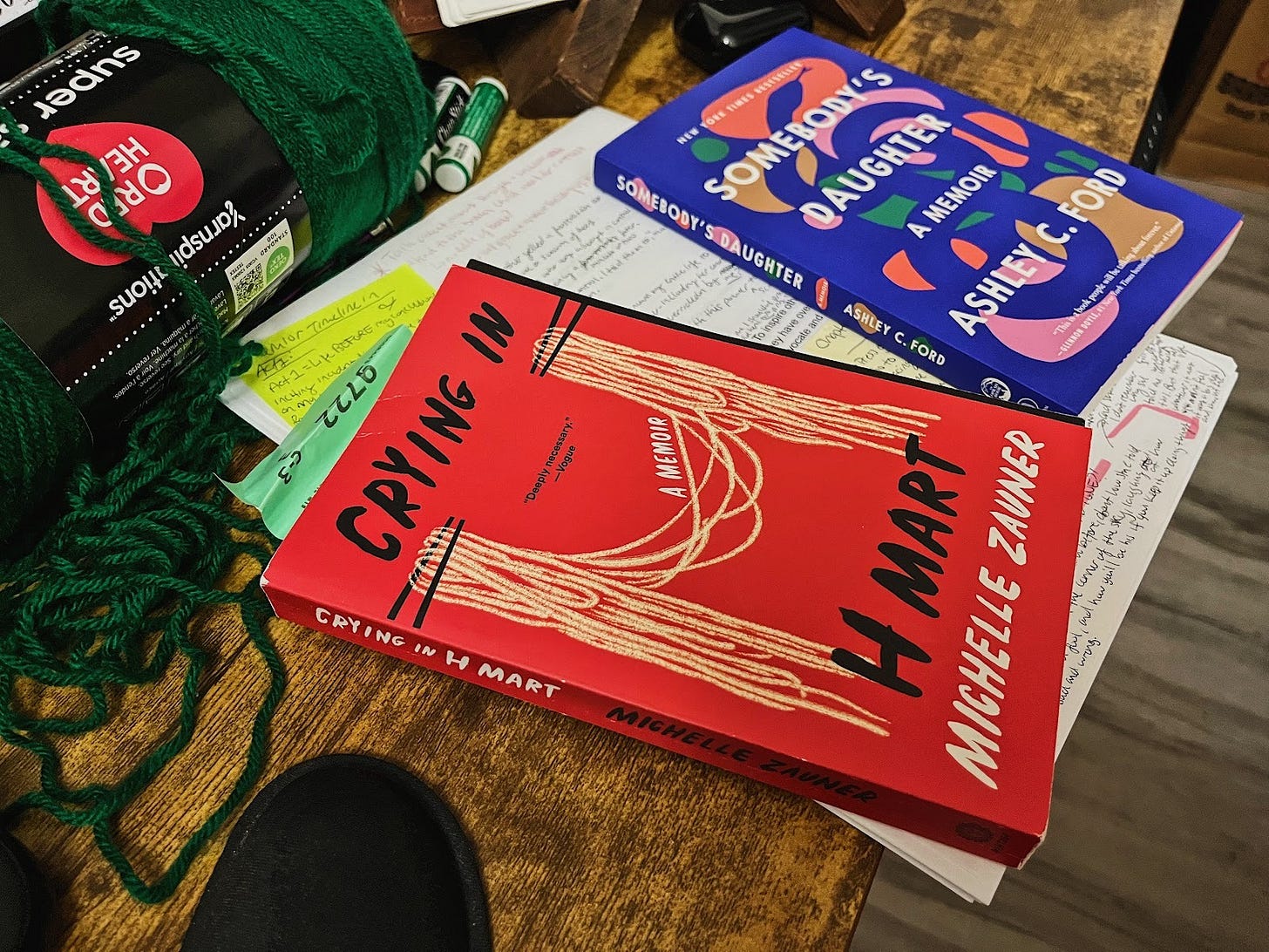 Two books sitting on a desk, on top of printer paper filled with handwritten notes
