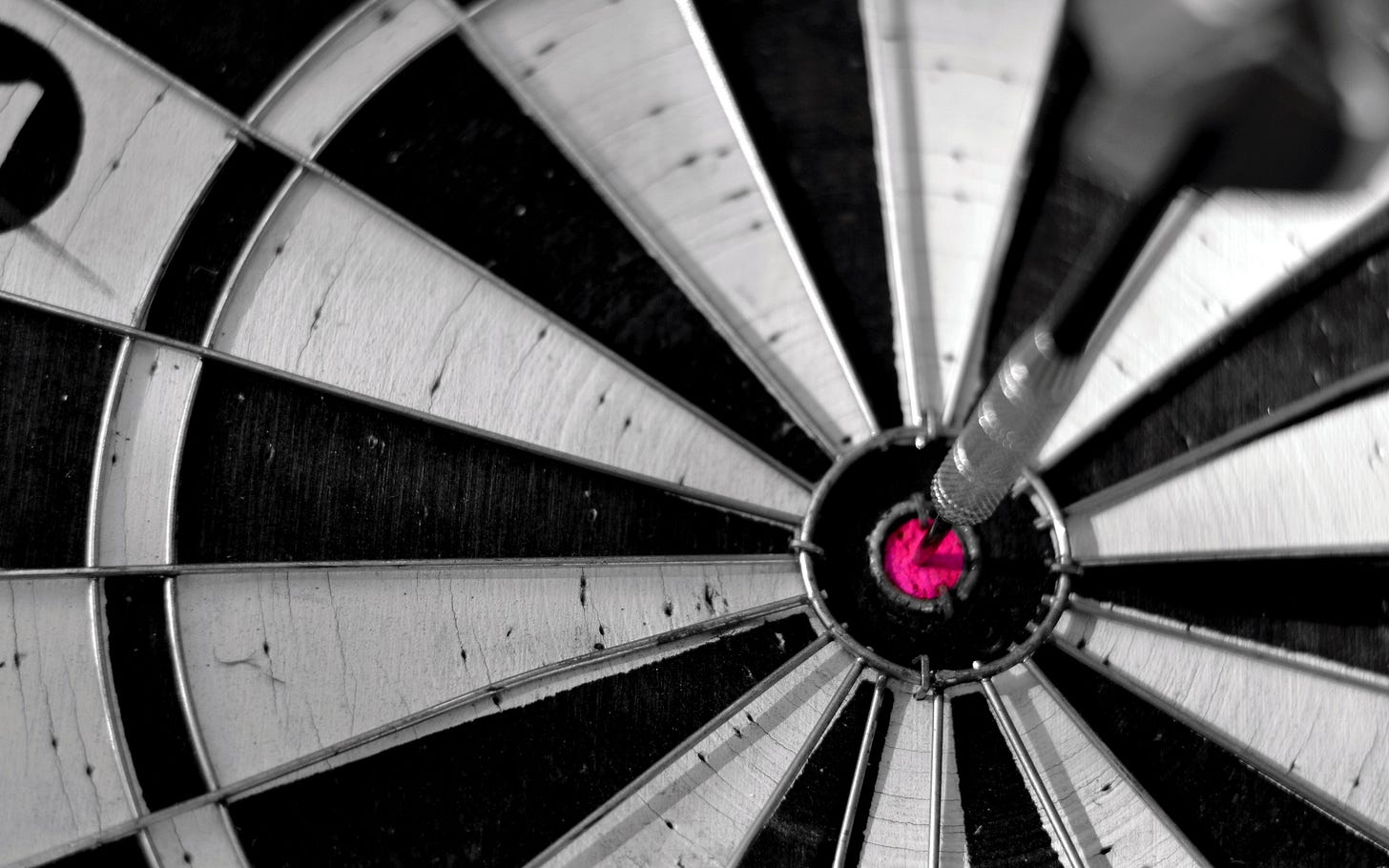 Close up photo of a black and white dartboard with a dart in a red bullseye Close up photo of a black and white dartboard with a dart in a red bullseye