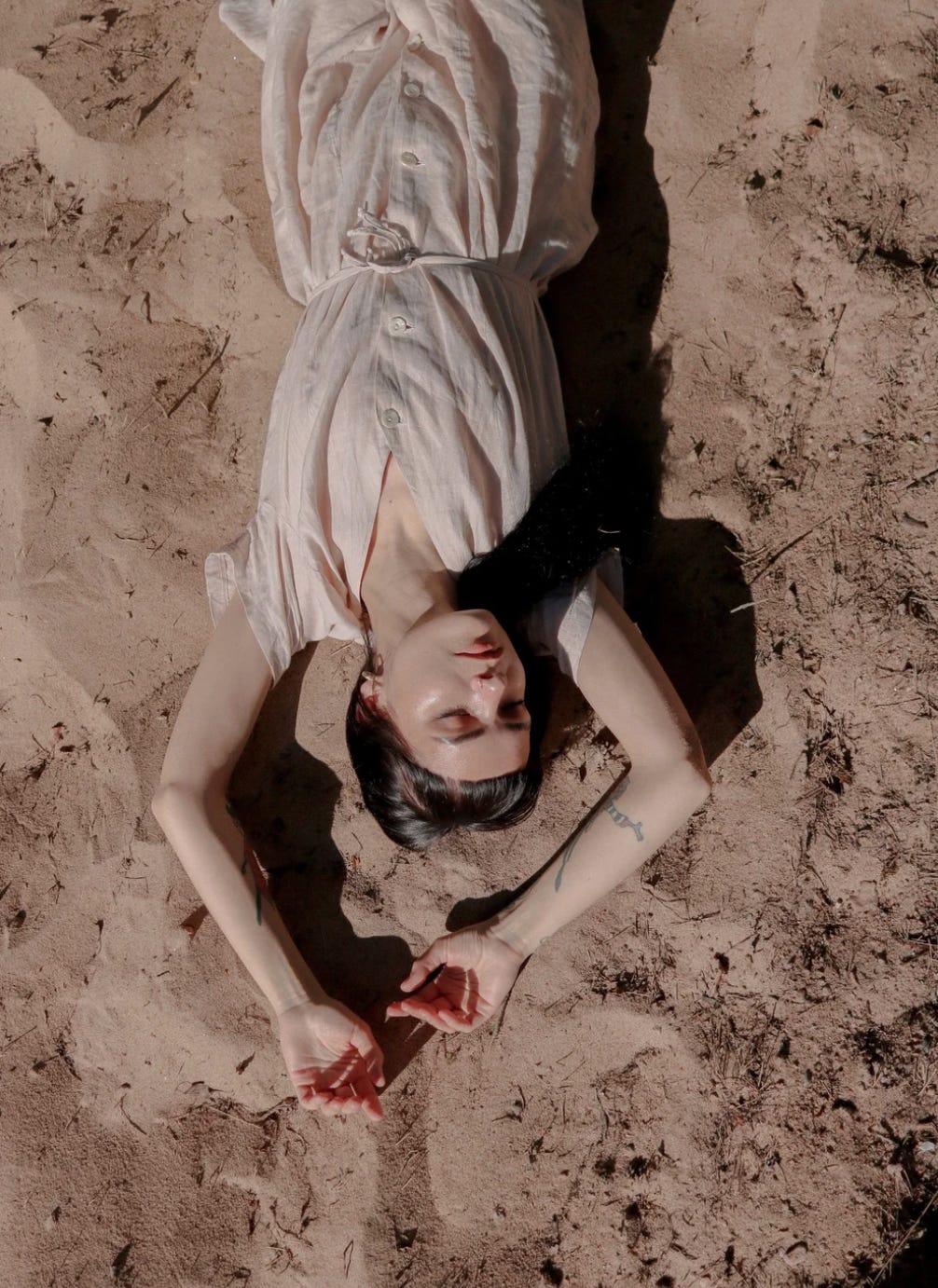 A woman reclines on a sandy landscape