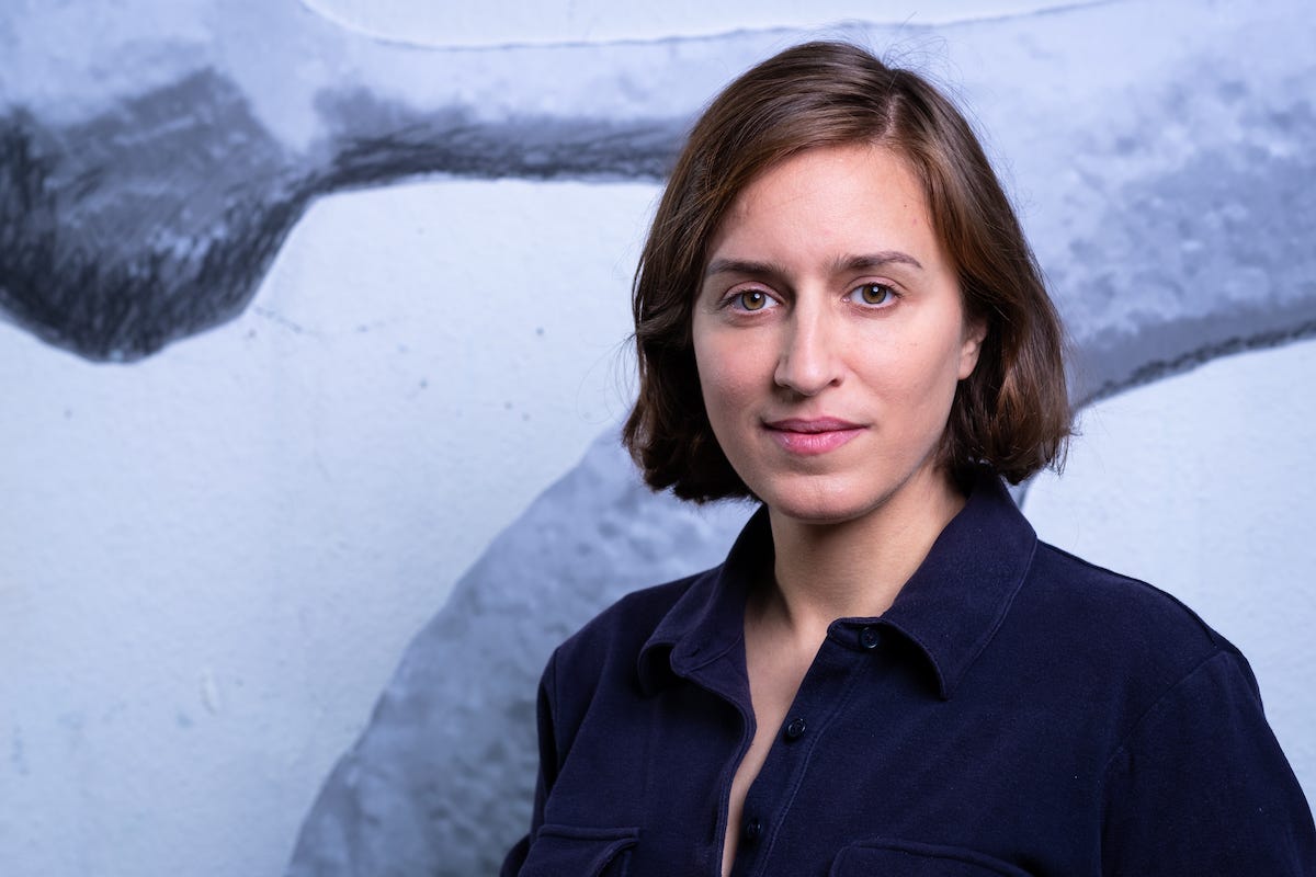 A woman with a bob standing in a blue wall. A woman with a bob standing in a blue wall.