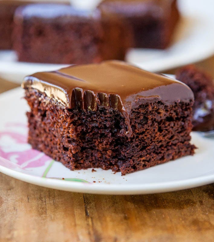 A slice of homemade chocolate ganache cake on a plate with a corner bite missing. A slice of homemade chocolate ganache cake on a plate with a corner bite missing.