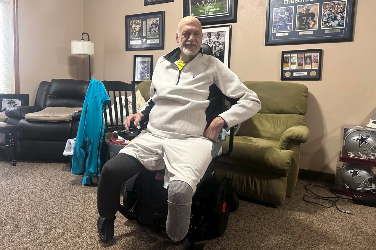 A photo of a man inside an apartment, seated in a wheelchair. A photo of a man inside an apartment, seated in a wheelchair.