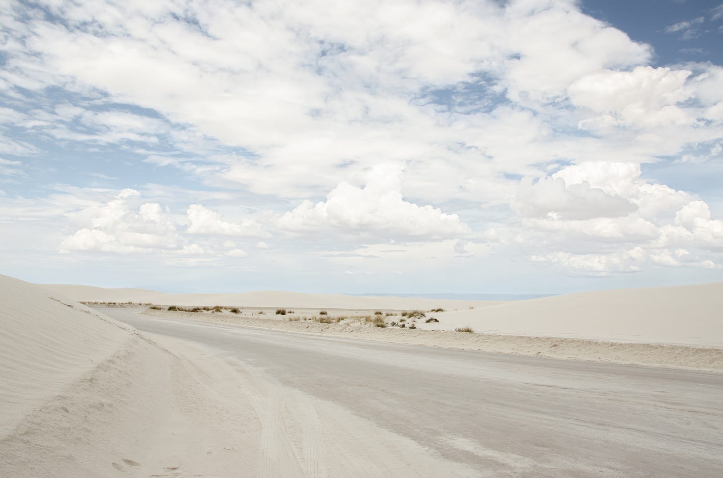 Image of white sands on a roadway with blue sky and white clouds in the background. 
