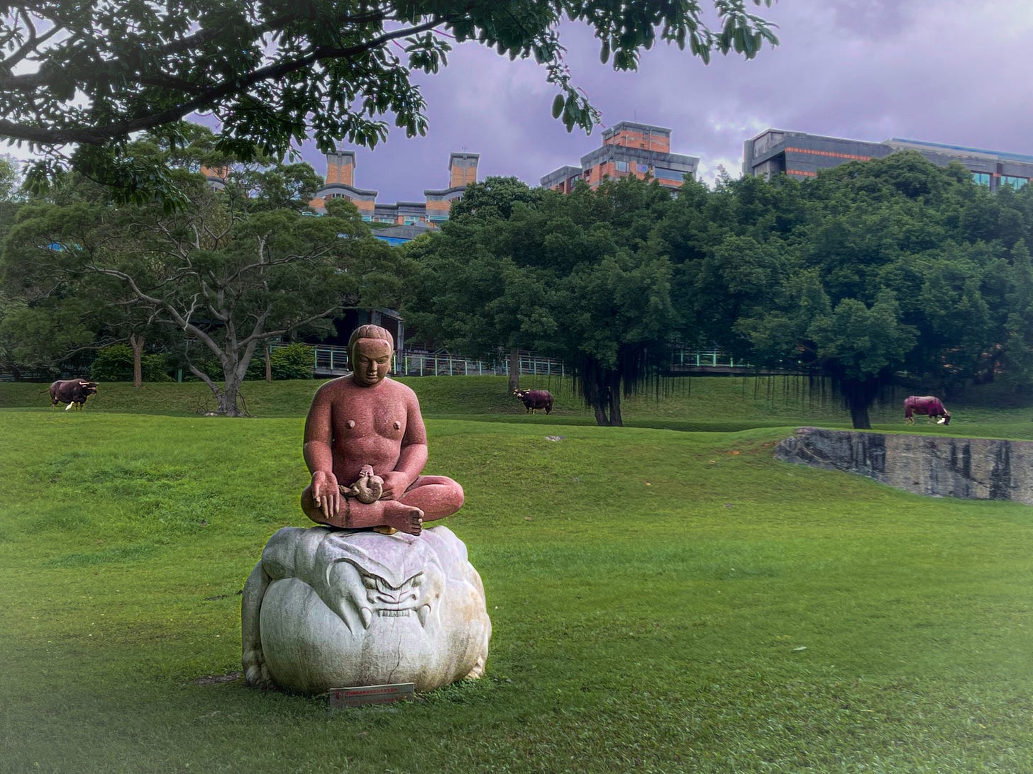 Three water buffalo graze behind a large Buddha statue at Taipei National University of the Arts Three water buffalo graze behind a large Buddha statue at Taipei National University of the Arts