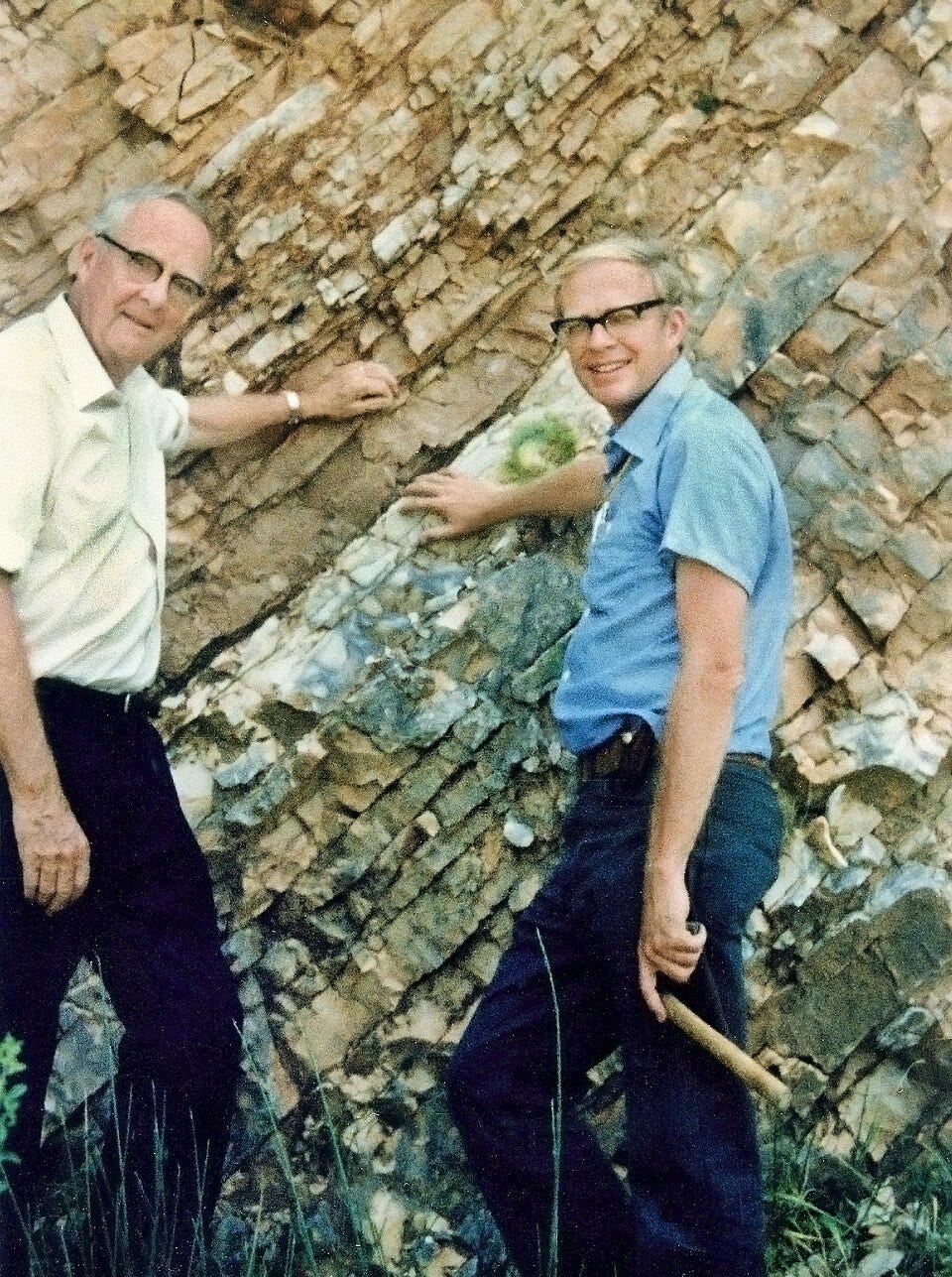Physicist Luis Alvarez and geologist Walter Alvarez stand beside an exposed rock outcrop in Gubbio, Italy, pointing to the thin clay layer that marks the K–Pg (formerly K–T) Boundary. Their work on this distinctive geologic layer, enriched in iridium, led to the groundbreaking hypothesis that a massive asteroid impact caused the extinction that ended the Age of Dinosaurs 66 million years ago.
