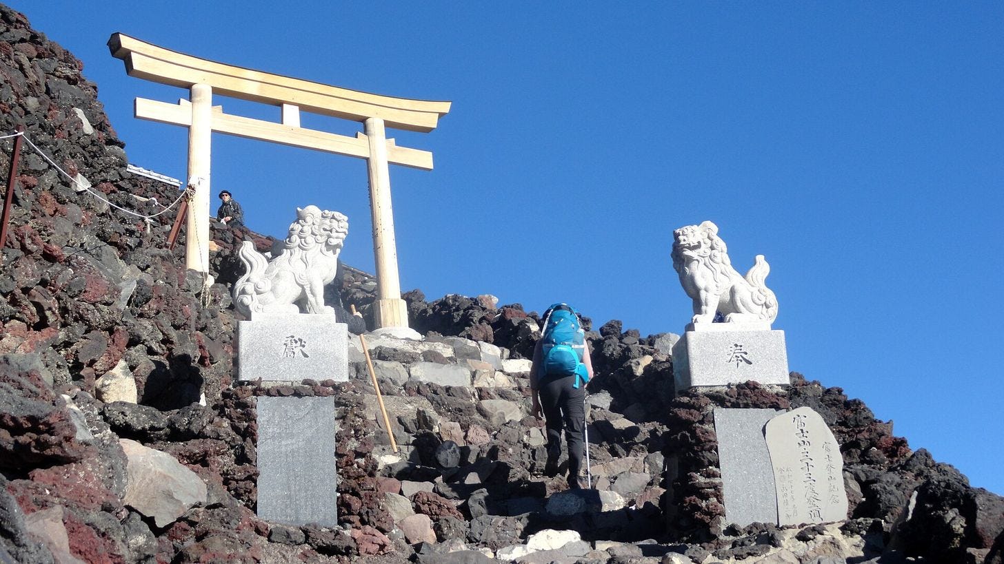 A climber passing the torii gate at the summit of Mount Fuji