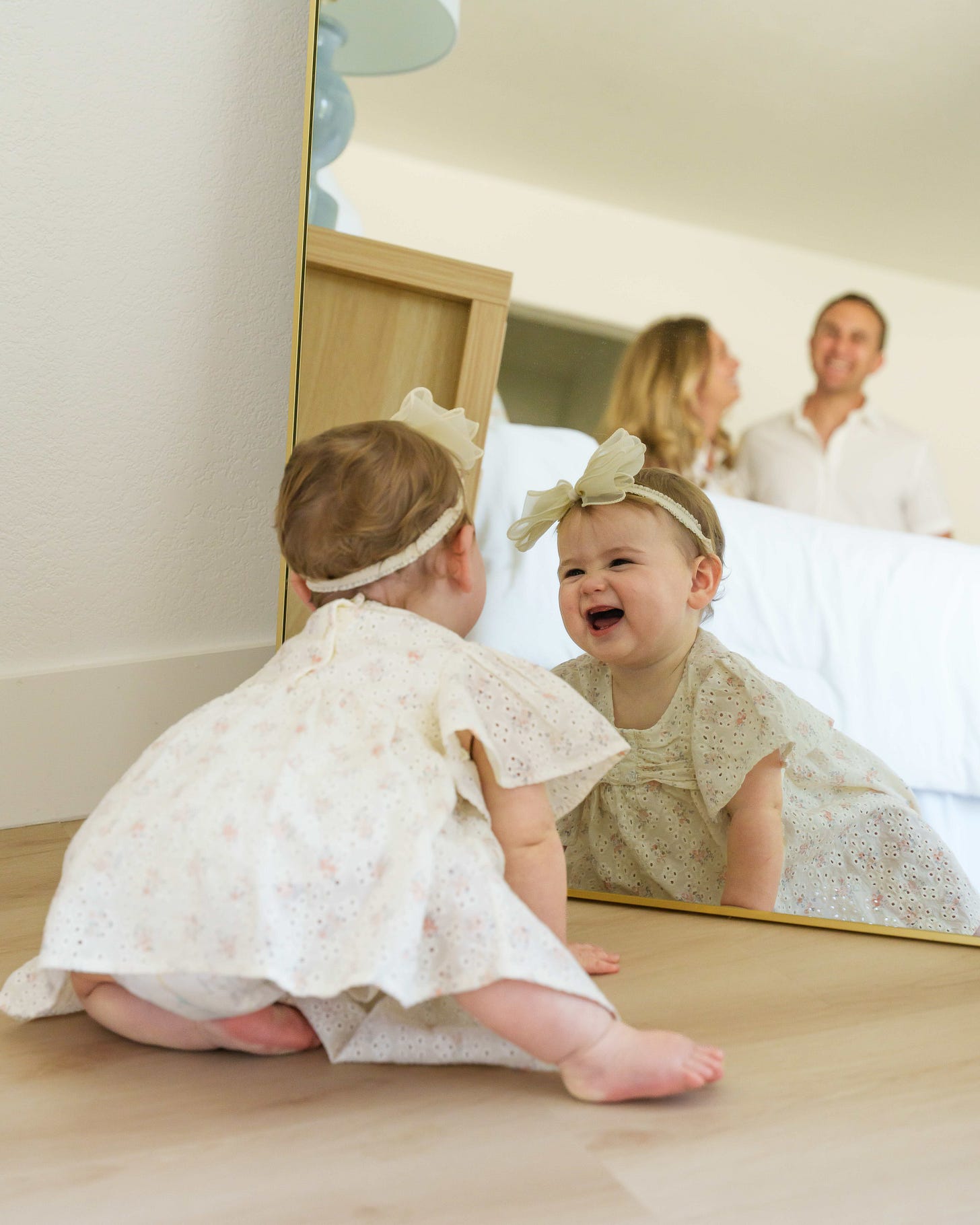 Zoe on the bedroom floor smiling into a mirror with Michelle and Aviv in the background Zoe on the bedroom floor smiling into a mirror with Michelle and Aviv in the background