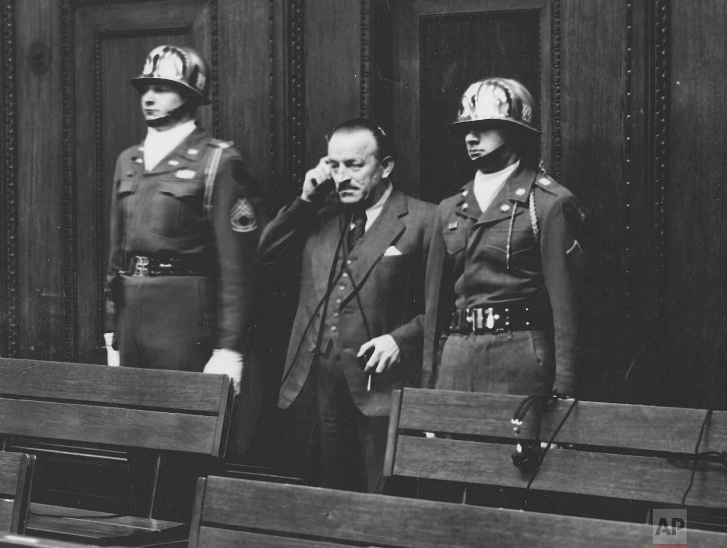 Paul Pleiger receives a 15-year prison sentence, flanked by U.S. Army honor guards Sgt. Thomas H. Andress and Pfc. Charles E. Auxilien of the 16th Infantry Regiment, at Nuremberg.