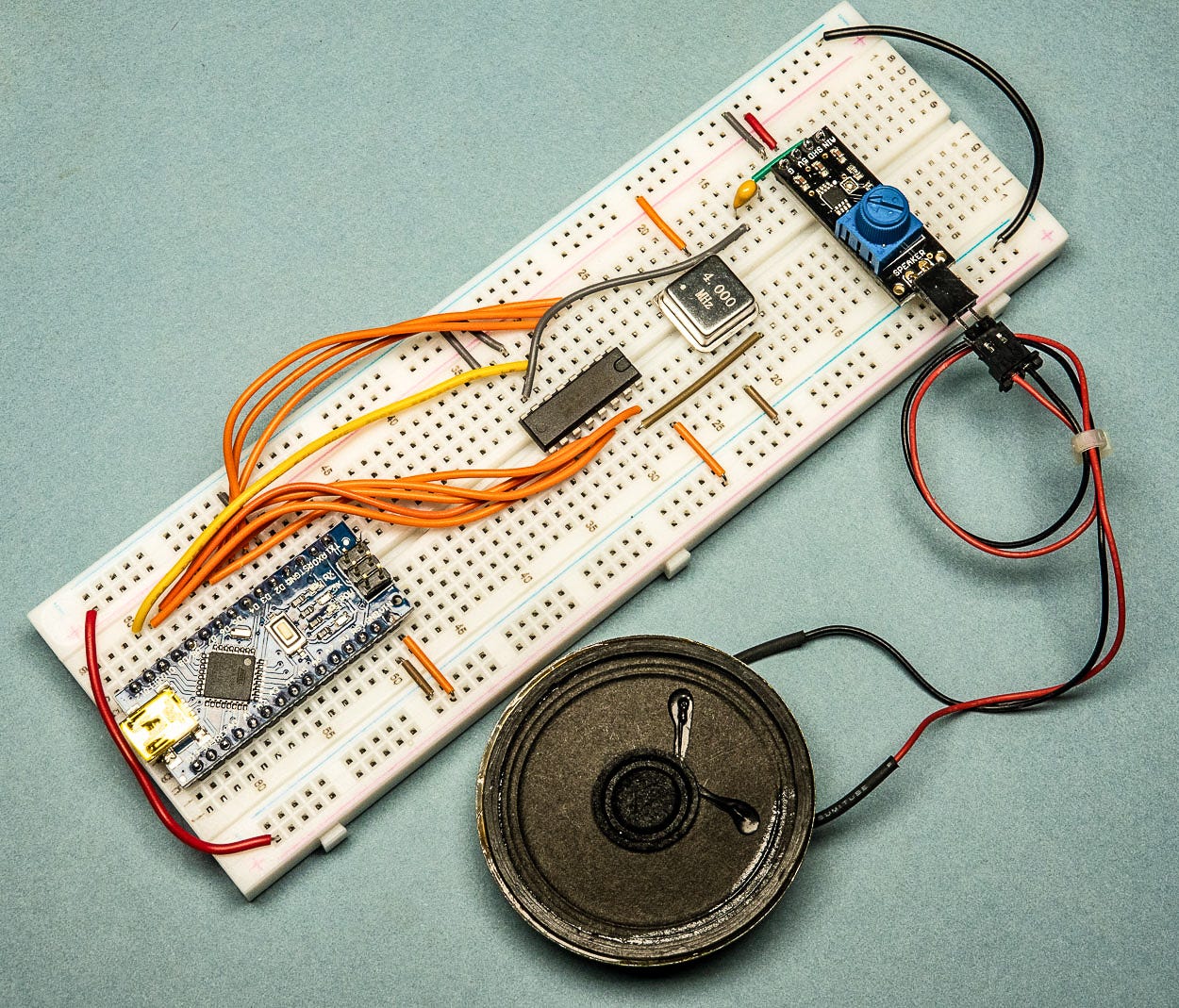 Photograph of an electronics prototyping breadboard with a microcontroller, chip, oscillator, amplifier and speaker