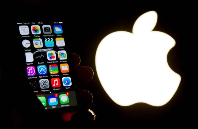 Un iPhone face au logo d’Apple, le 30 janvier 2015 à Lille.