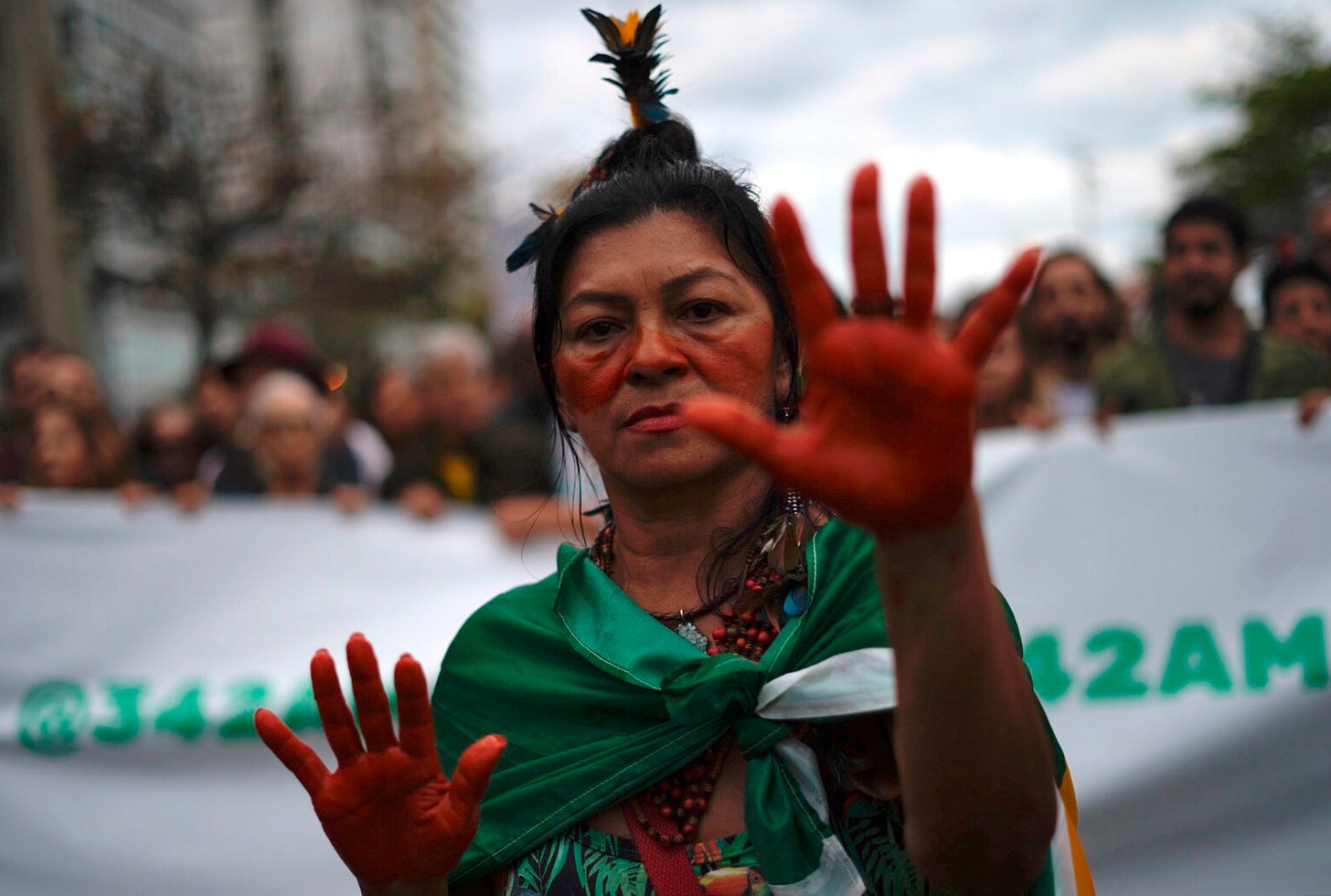 Closeup of Indigenous woman, hands raised painted red in front of a crowd of protestors. Closeup of Indigenous woman, hands raised painted red in front of a crowd of protestors.