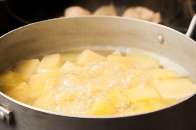 Cut the potatoes into uniform chunks and place them in a heavy saucepan along with the garlic. Cover with water, bring to a boil, lower heat to medium, and cook until the potatoes are fork-tender for about 20 minutes. [2]