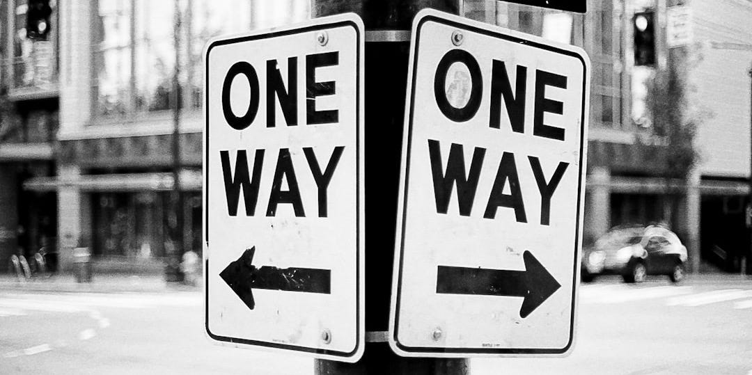 a one way sign on a pole on a city street a one way sign on a pole on a city street