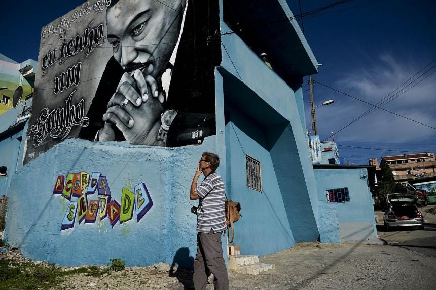A tourist stands in front of a Martin Luther King graffiti in the Cova da Moura neighborhood of Amadora on the outskirts of Lisbon. One of the most ill reputed suburban neighborhoods of Europe, it is often likened to the favelas of Brazil and the tow A tourist stands in front of a Martin Luther King graffiti in the Cova da Moura neighborhood of Amadora on the outskirts of Lisbon. One of the most ill reputed suburban neighborhoods of Europe, it is often likened to the favelas of Brazil and the tow